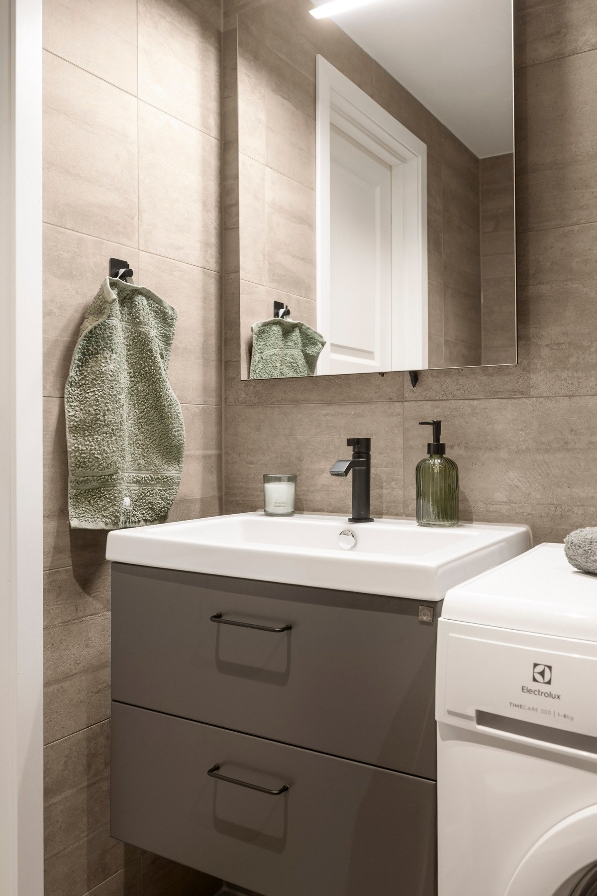 Badet har vegghengt servantinnredning med skuffer og ovenpåliggende servant, samt speil med belysning på vegg over servant. Galleribilde