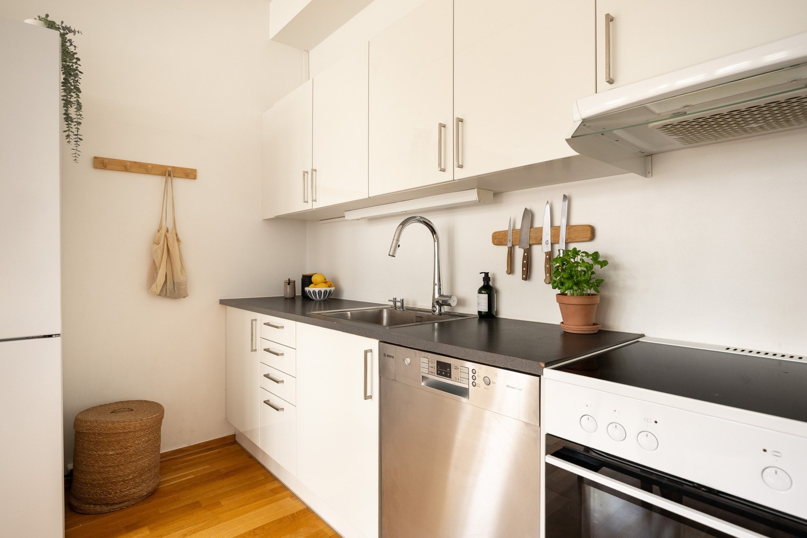 Pent kjøkken med glatte lyse fronter og benkeplate av laminat med oppvaskkum av rustfritt stål. Galleribilde