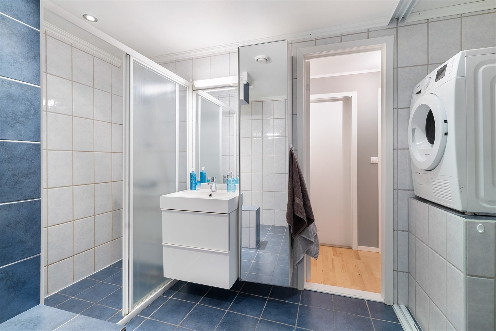 Boligen har et stort, flislagt baderom med moderne innredning og vaskesone gjemt bak skyvedør. Galleribilde