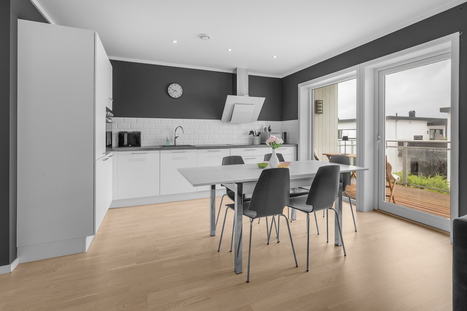 Moderne kjøkken med stilrene fronter, flislagt vegg og direkte utgang til solrik veranda. Galleribilde