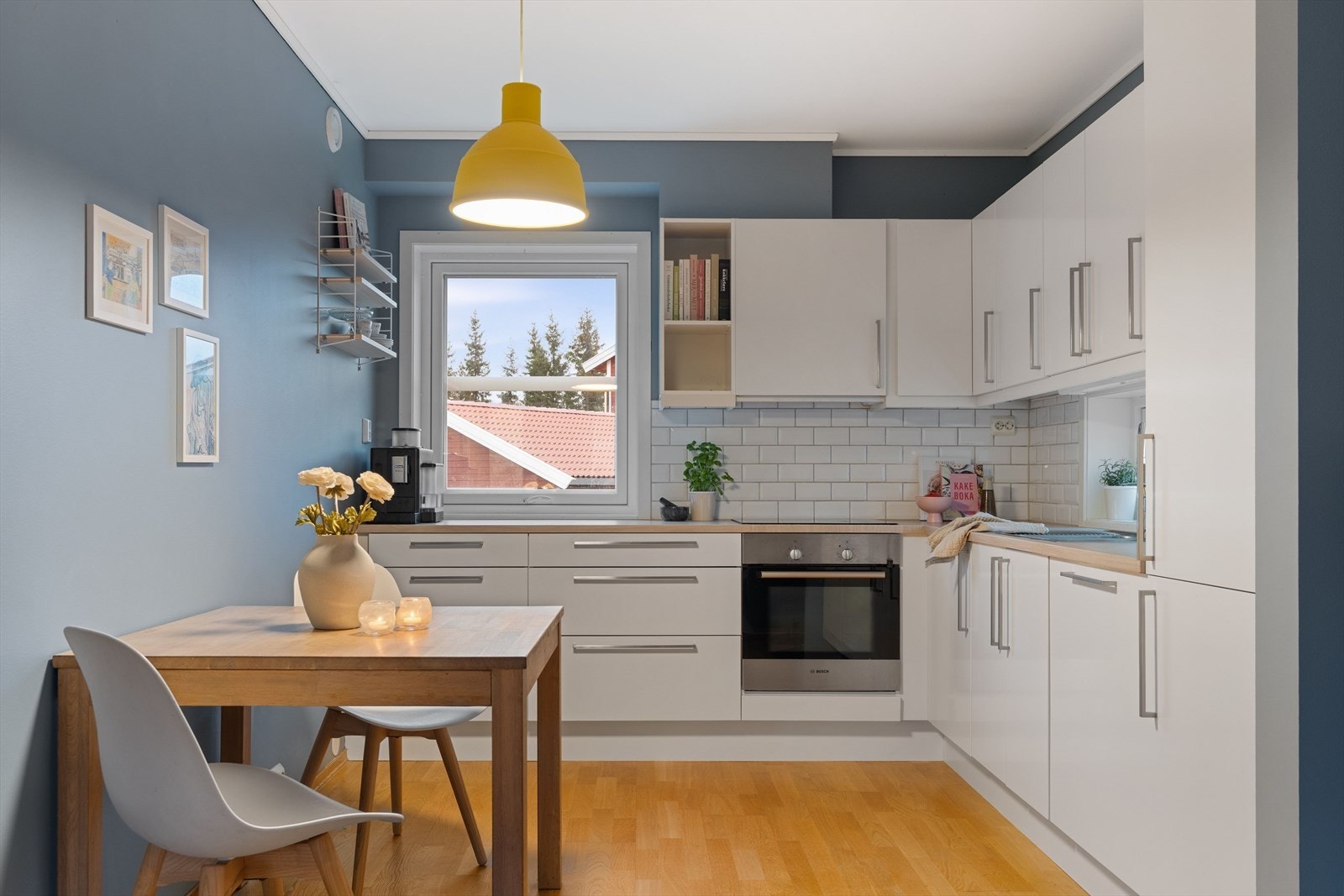 Kjøkkeninnredningen har glatte, lyse fronter med god skap- og benkeplass, og overflaten er lettstelt med fliser mellom benk og overskap. Galleribilde