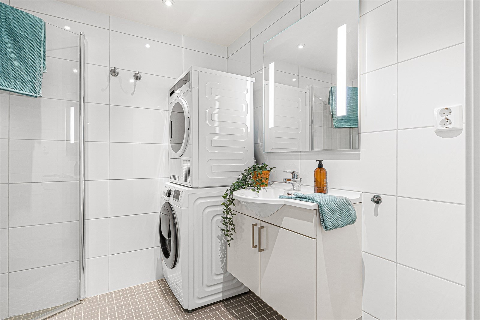 Boligens baderom er utstyrt med innfellbare dusjdører i dusjhjørne, rørfordelerskap, mekanisk avtrekk, veggmontert toalett, servant i skap og opplegg for vaskemaskin. Galleribilde