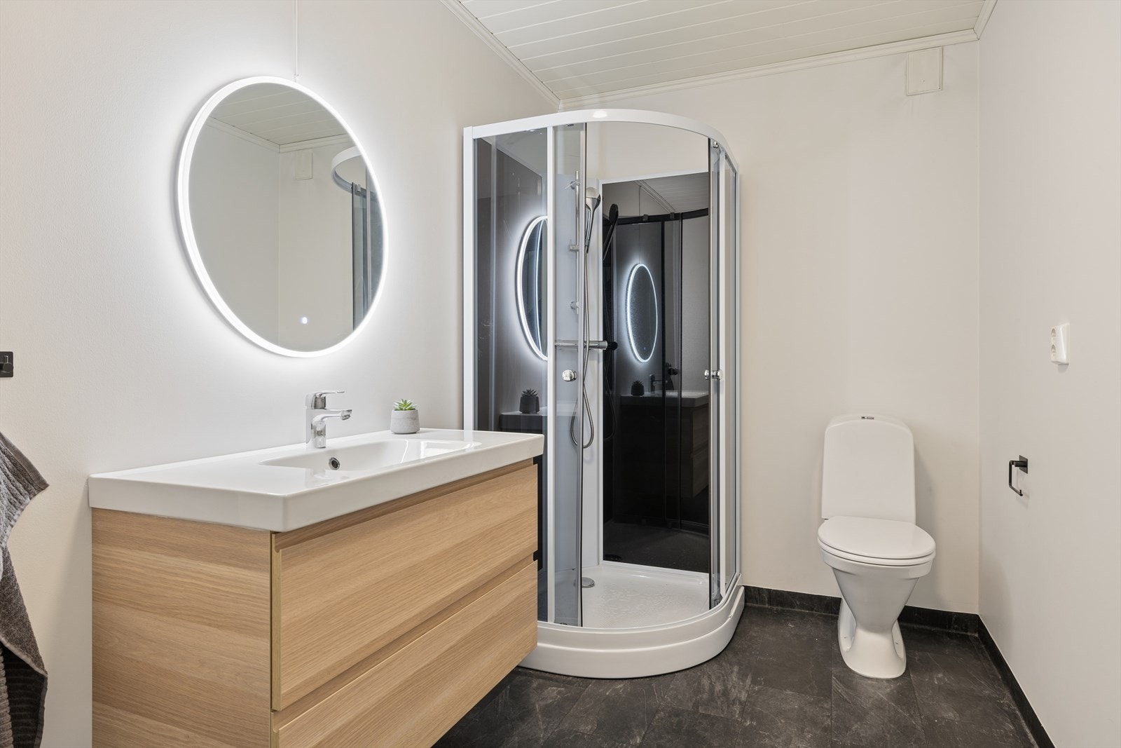 Nyere bad fra 2020 med vannbåren varme i gulvet. Badet er innredet med toalett, dusjkabinett, baderomsinnredning med servant og speil. Galleribilde