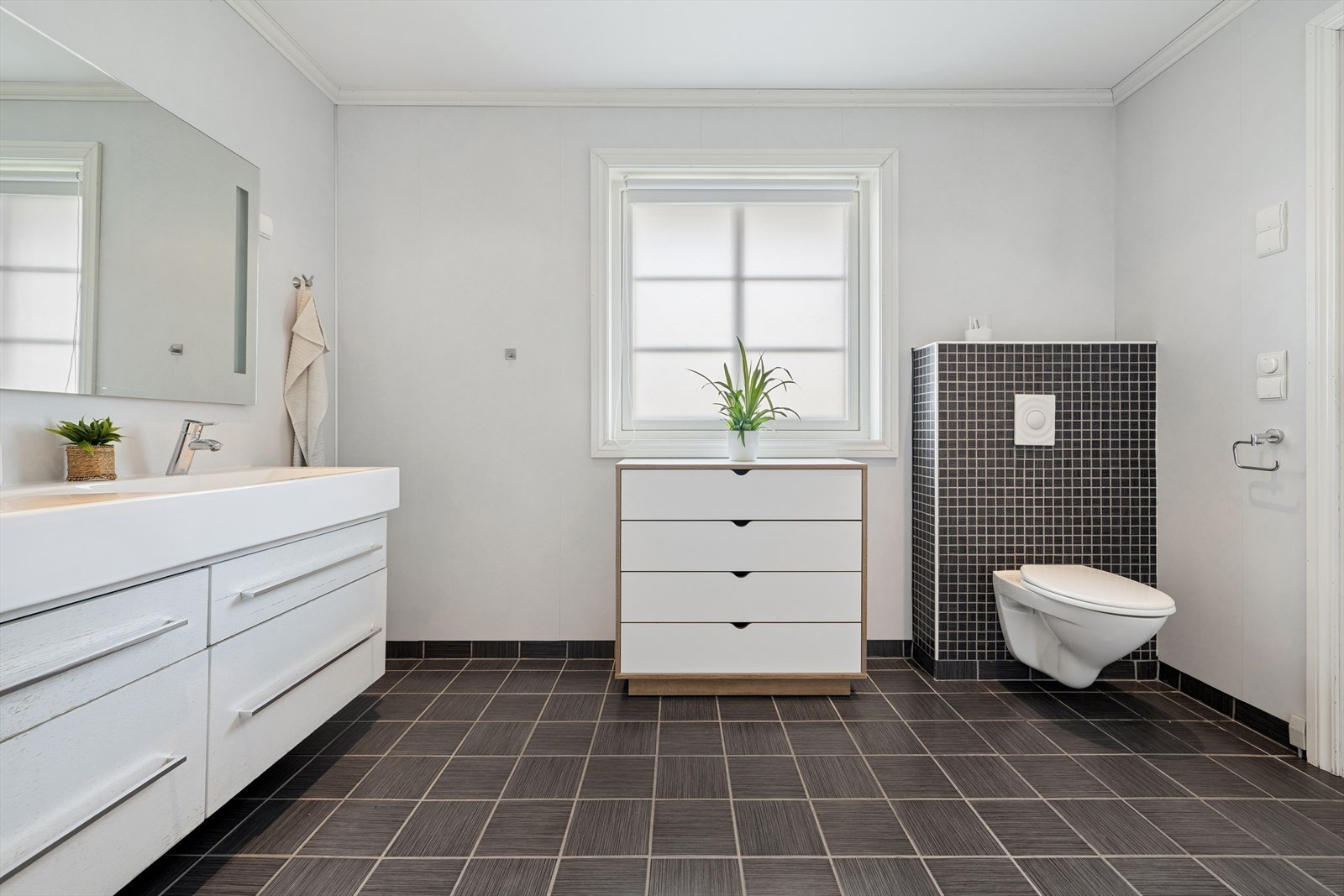 Badet er innredet med vegghengt toalett, dusjkabinett, baderomsinnredning med dobbel servant og stort speil. Galleribilde