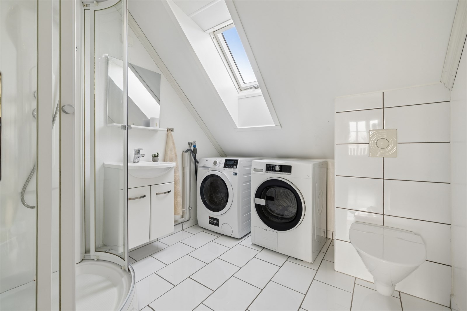 Lyst og praktisk bad med flislagt gulv som har behagelig varme i gulvet. Badet er innredet med vegghengt toalett, dusjkabinett, innredning med servant samt opplegg for vaskemaskin. Galleribilde