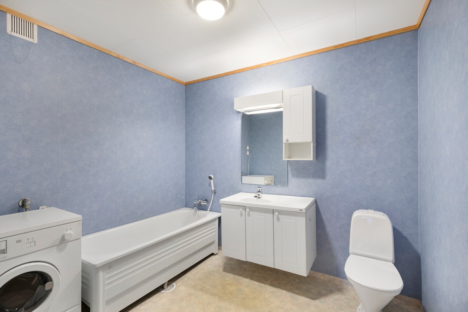 Bad/vaskerom i underetasjen med gulvvarme, baderomsinnredning, badekar, toalett og opplegg for vaskemaskin Galleribilde