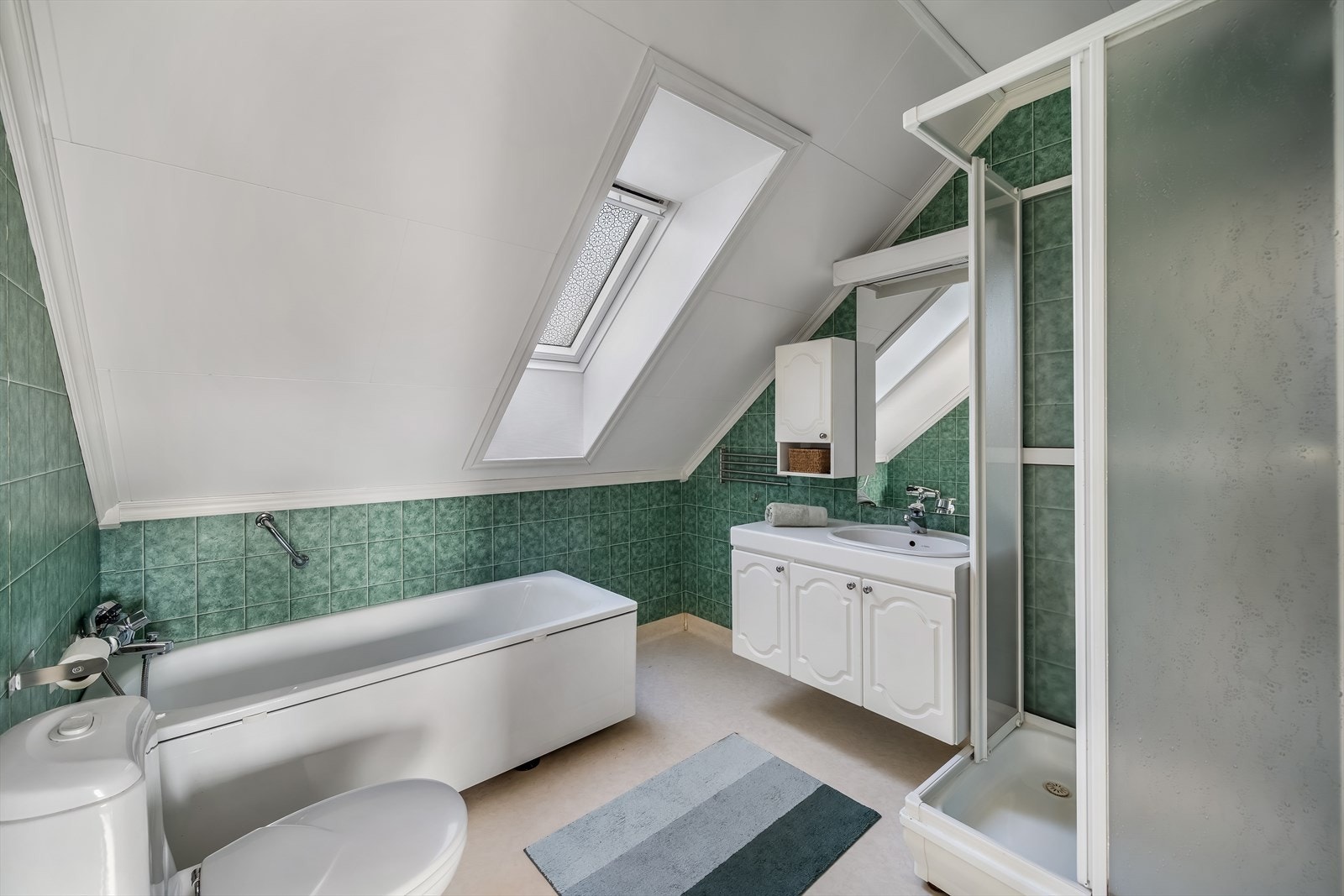 Baderom i 2.etasje. Her er det belegg på gulv og baderomstapet på vegg. Innredet med baderomsinnredning, toalett, badekar og dusjkabinett. Galleribilde