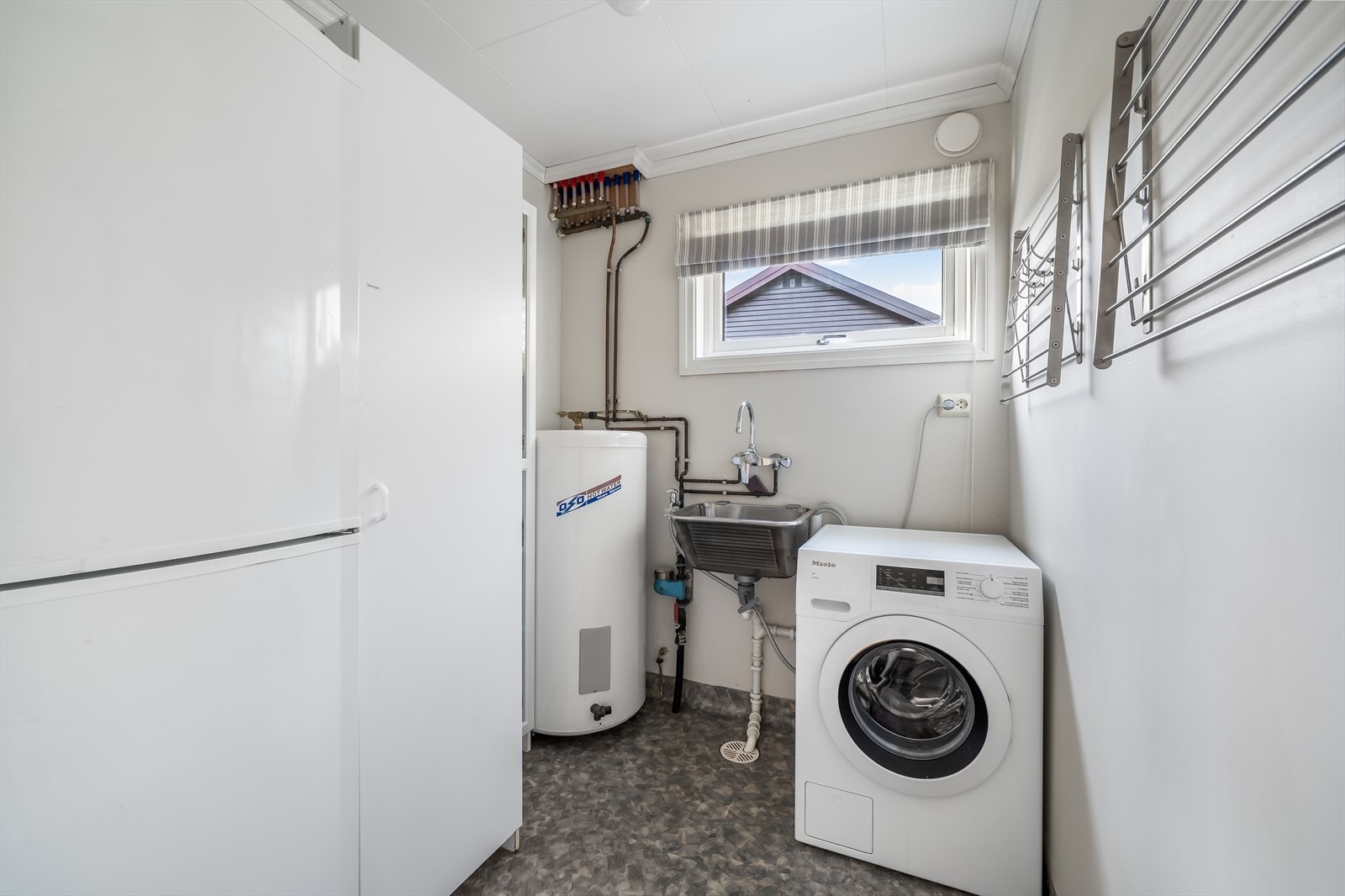 Praktisk vaskerom med opplegg for vaskemaskin, samt god plass til annen oppbevaring. Galleribilde