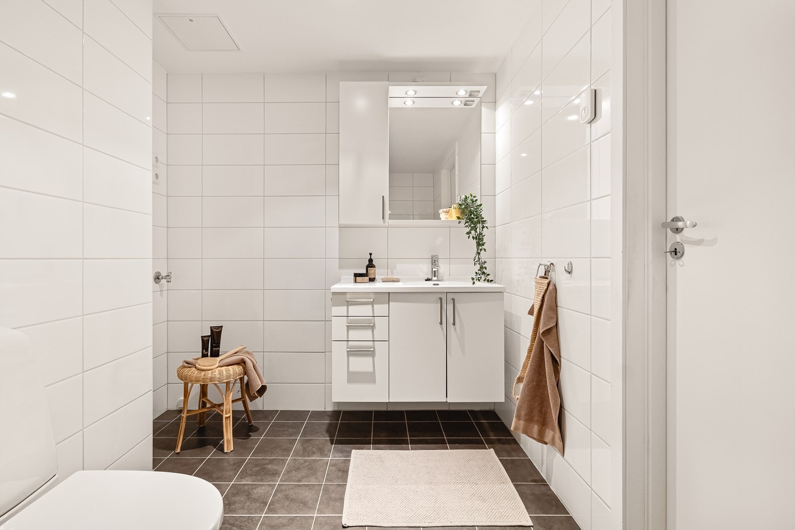 Baderomsinnredning med heldekkende servant med oppbevaring, speil og belysning. Her er også opplegg for vaskemaskin og tørketrommel. Galleribilde