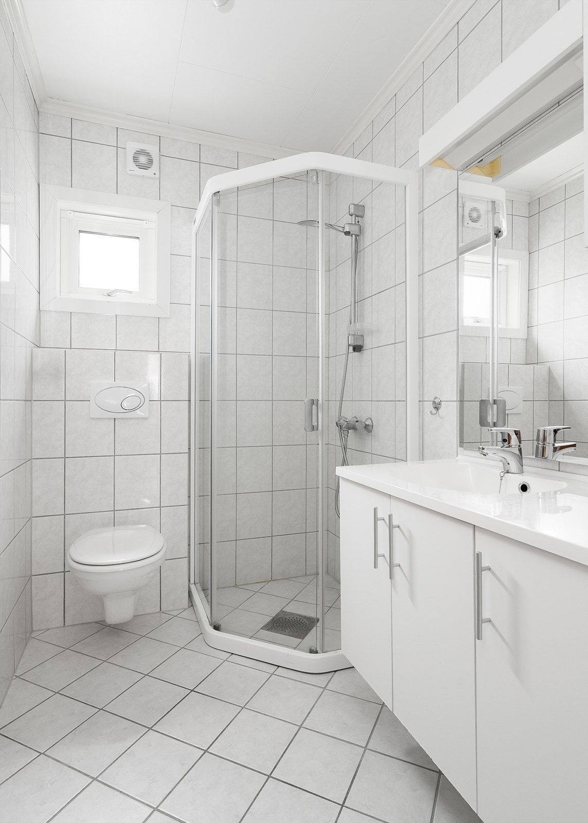 Badet i 1. etasje er fra 2009 og har flis på vegger og gulv. Hvit baderomsinnredning med god skapplass og heldekkende servant, samt speil med overlys. Badet er også innredet med dusjhjørne og veggmontert toalett. Galleribilde