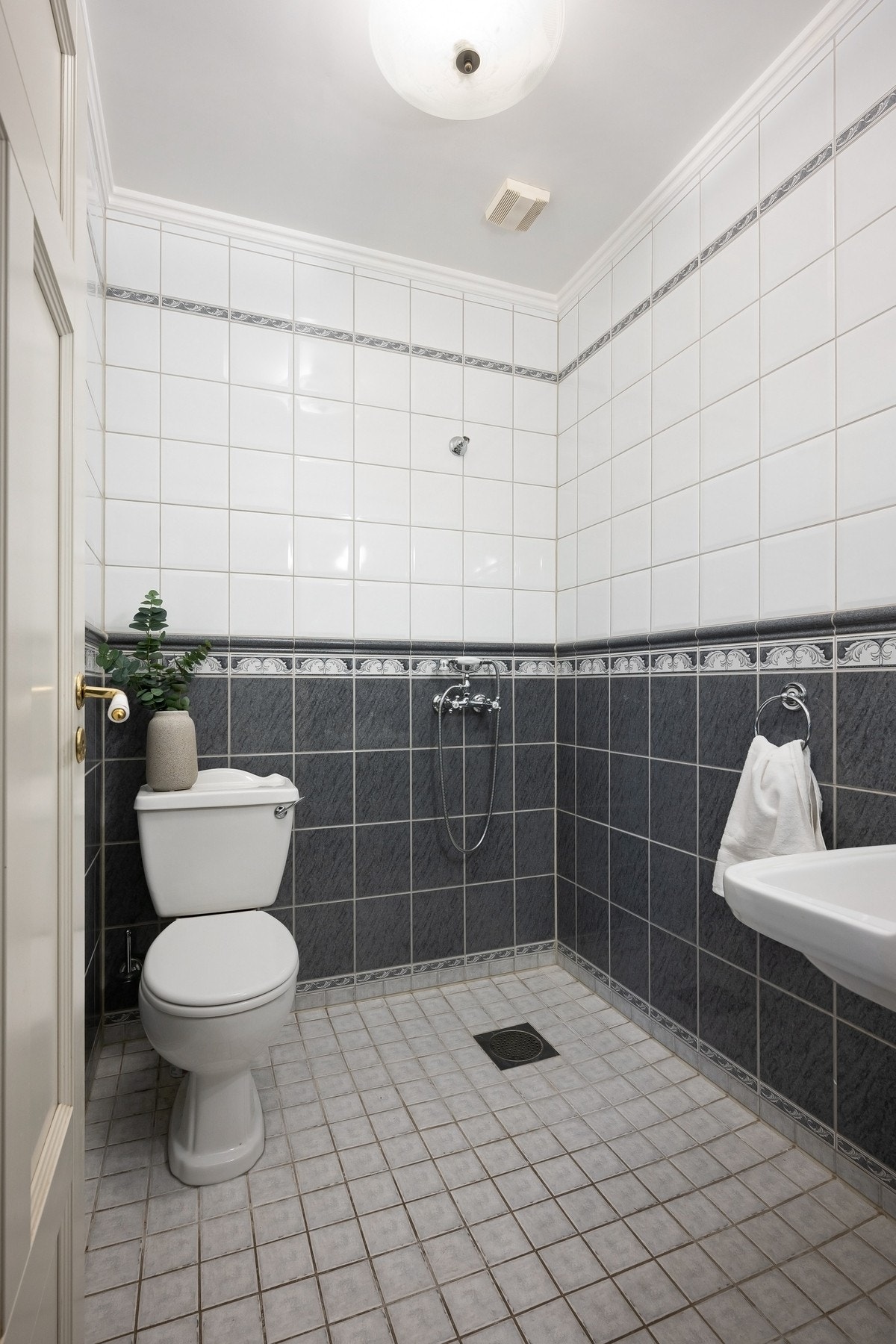 Eldre baderom i hovedetasjen, med flislagte flater. Badet er innredet med søyleservant, dusjhjørne og wc. Galleribilde