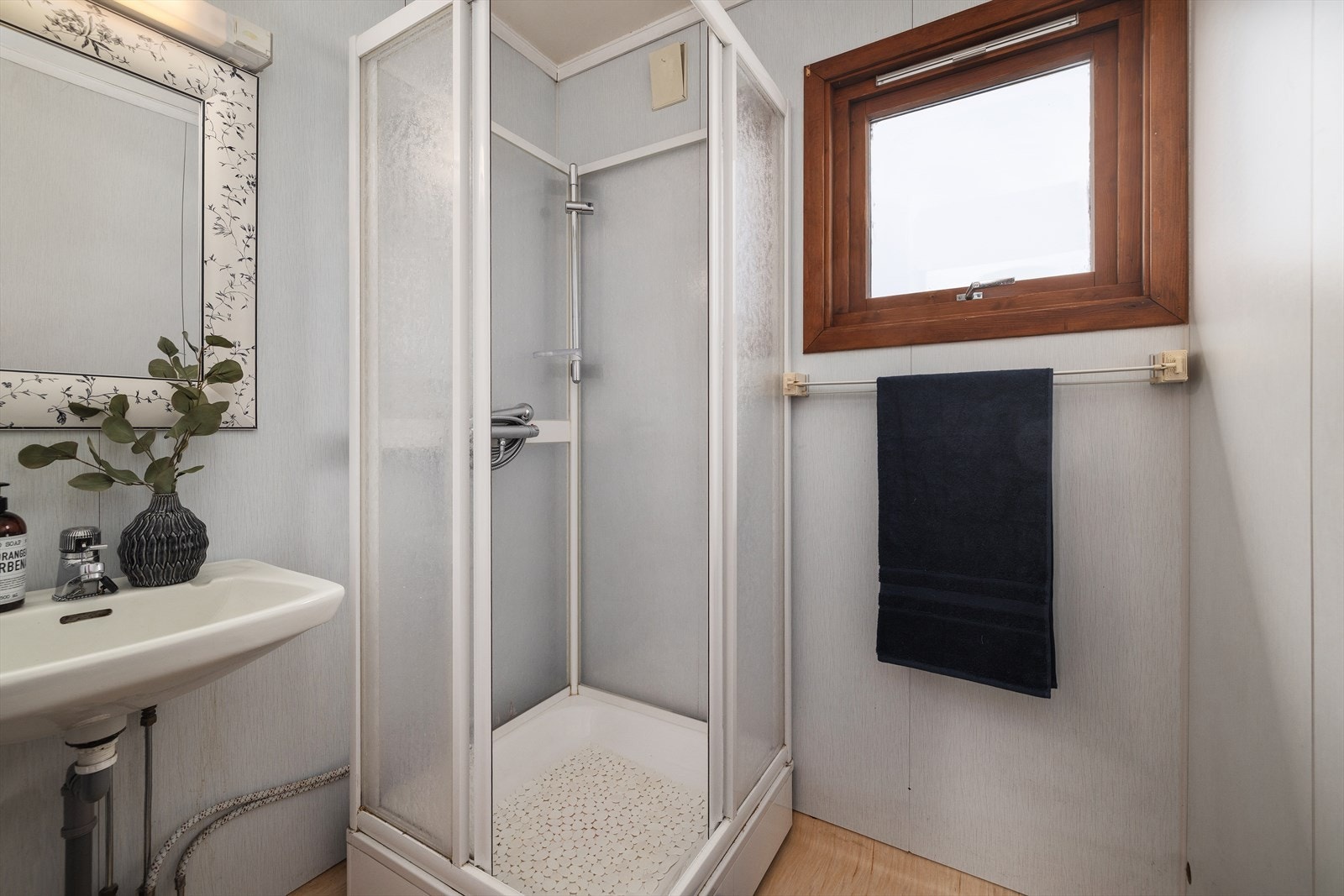 Badet er utstyrt med servant, dusjkabinett og har baderomsplater på veggene. Galleribilde