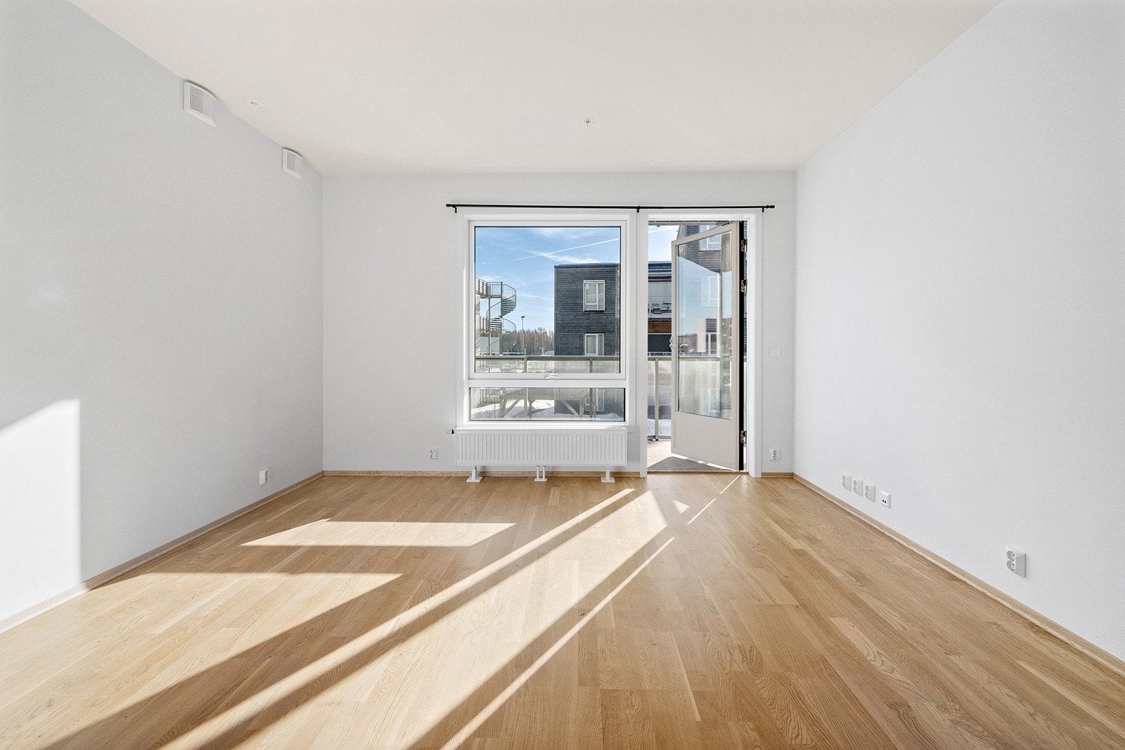 Lys og åpen stue med store vindusflater og adkomst til leilighetens sydøstvendte balkong Galleribilde