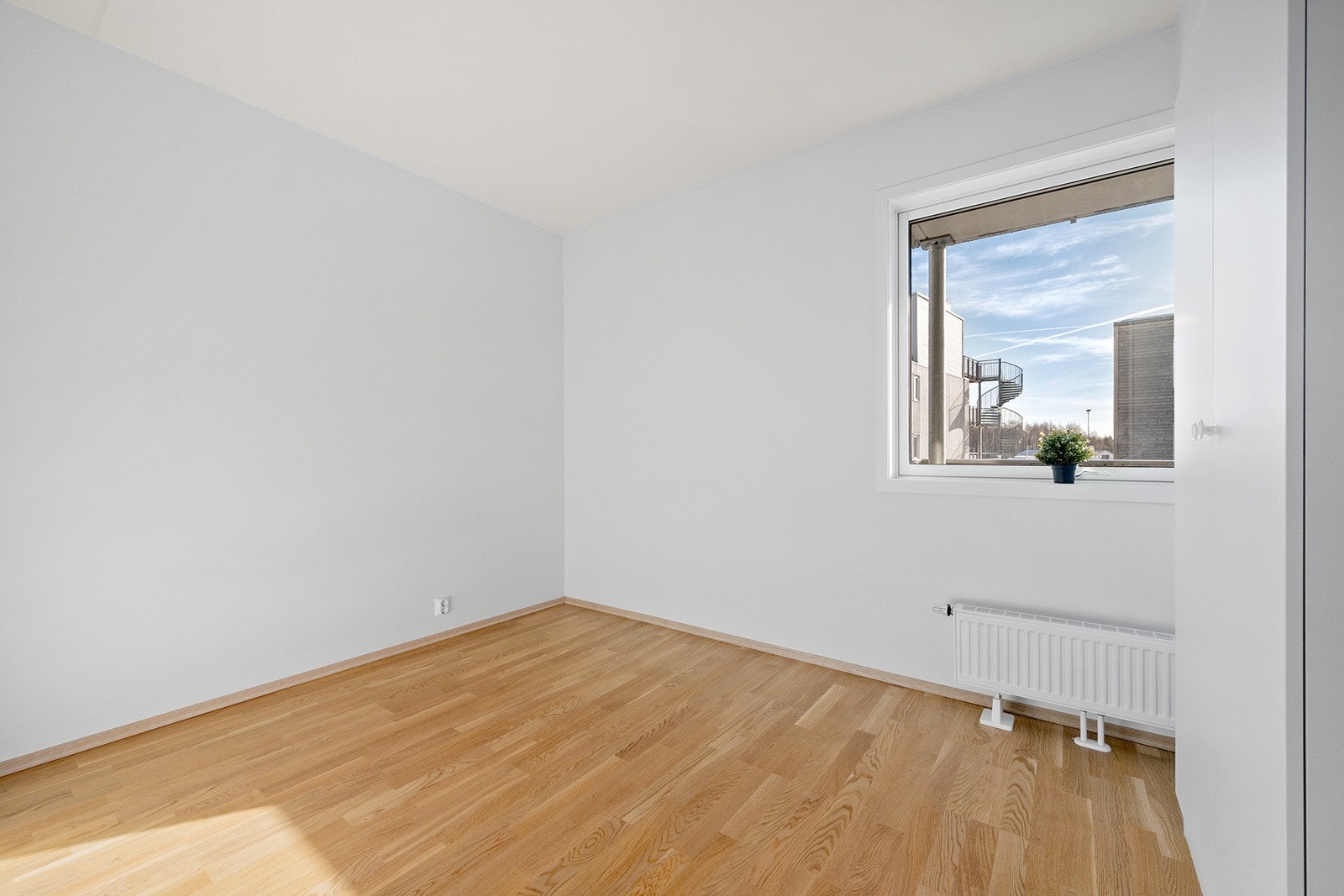 Romslig soverom med glatte lyse flater og 3-stavs eikeparkett Galleribilde