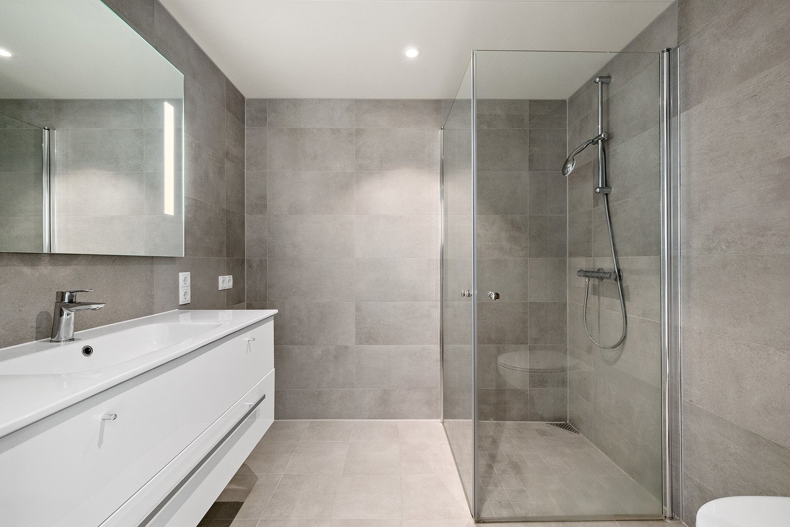 Moderne og stilrent bad med mørke fliser, downlights og gulvvarme Galleribilde