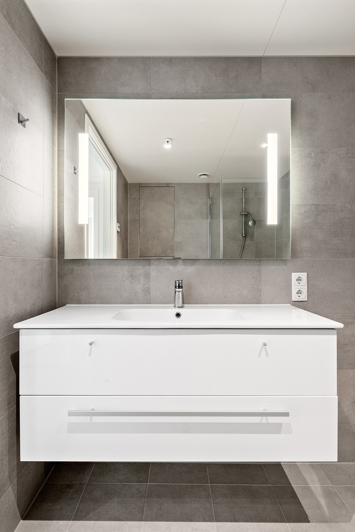 Badet har en moderne servant med skuffeseksjon for oppbevaring Galleribilde