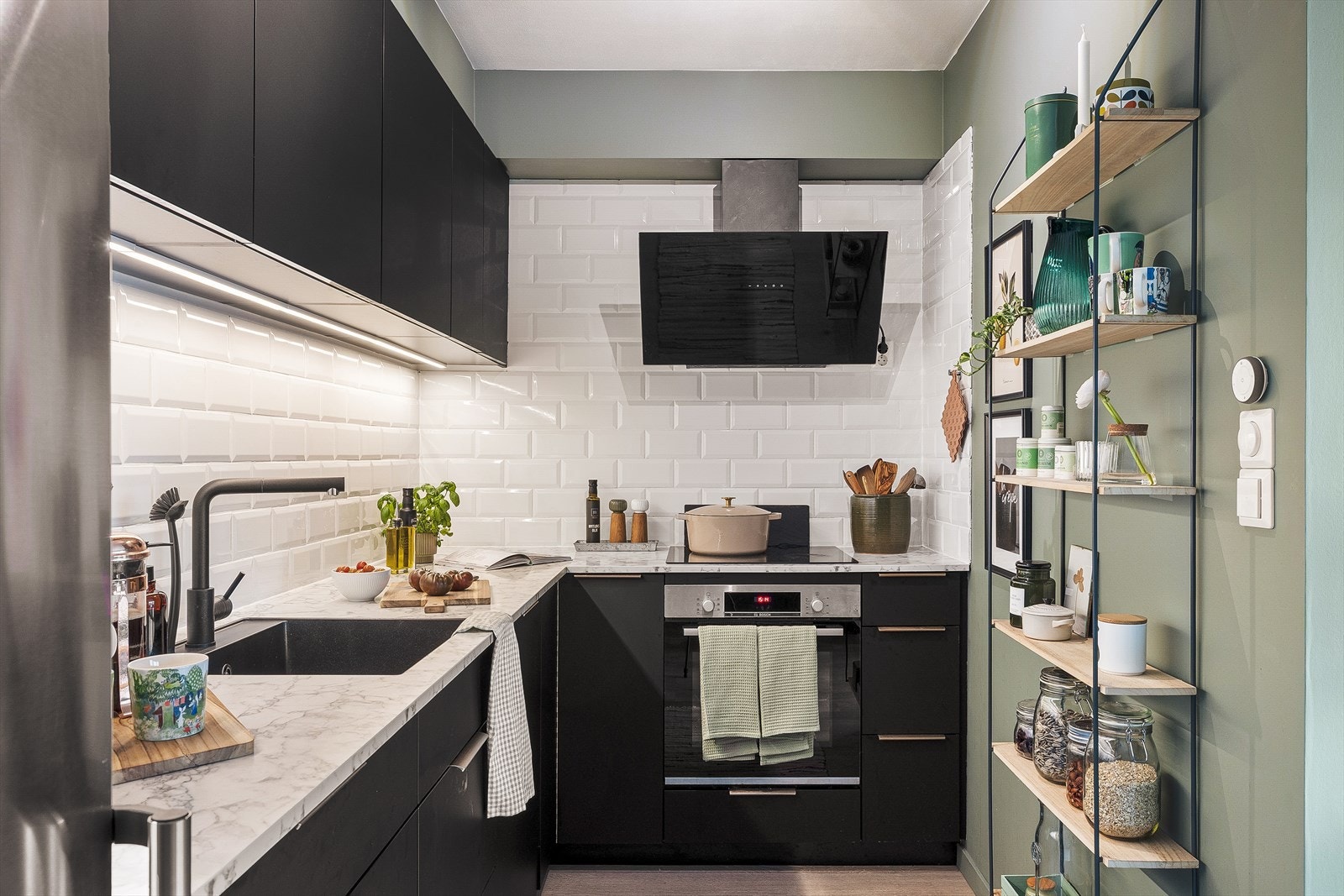 Kjøkkeninnredningen fra Kvik strekker seg langs veggen i en praktisk L-form og har en moderne fremtoning med glatte sorte fronter og overskap ført opp til tak. Galleribilde