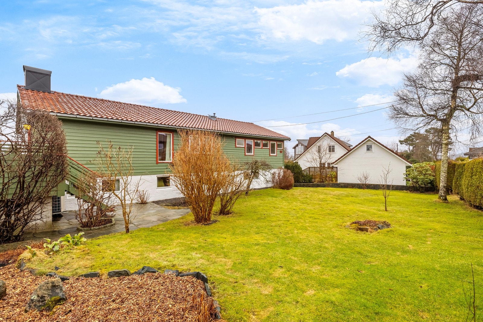 Fra terrassen går det trapp ned til baksiden av huset, og nedlagt sten gjør det enkelt å ta seg rundt på tomten Galleribilde