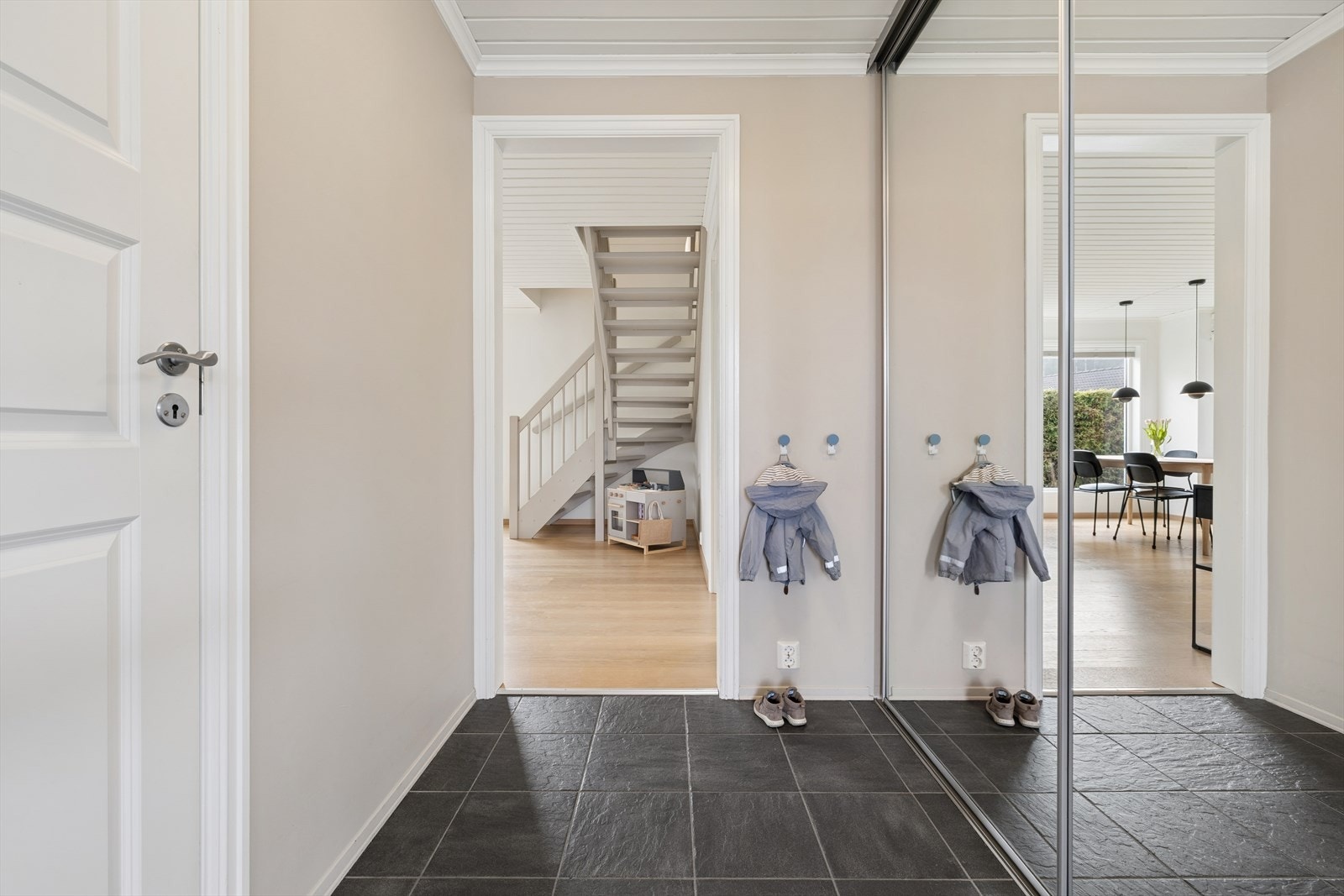 Her ønskes du velkommen inn i en lys, flislagt entré med god plass til å oppbevare ytterklær og sko i stor skyvedørsgarderobe med speildører. Galleribilde