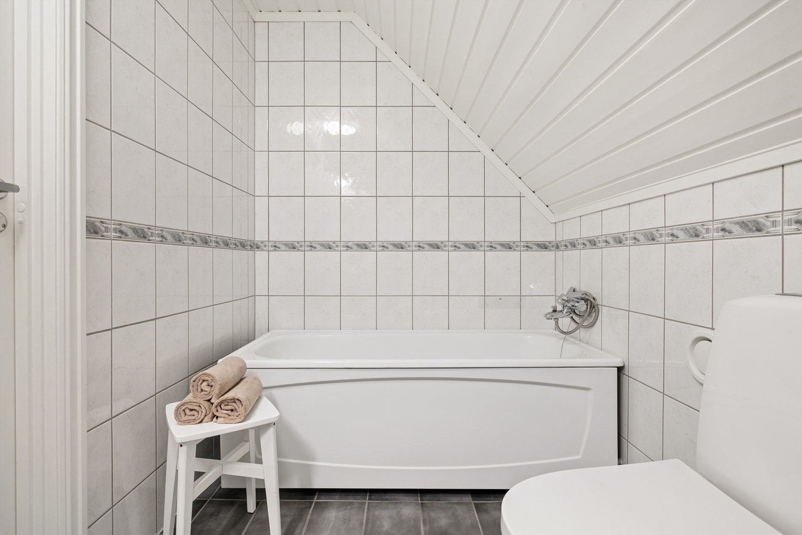 Badet er utstyrt med toalett, dusjkabinett, badekar og baderomsinnredning med servant og speil. Galleribilde