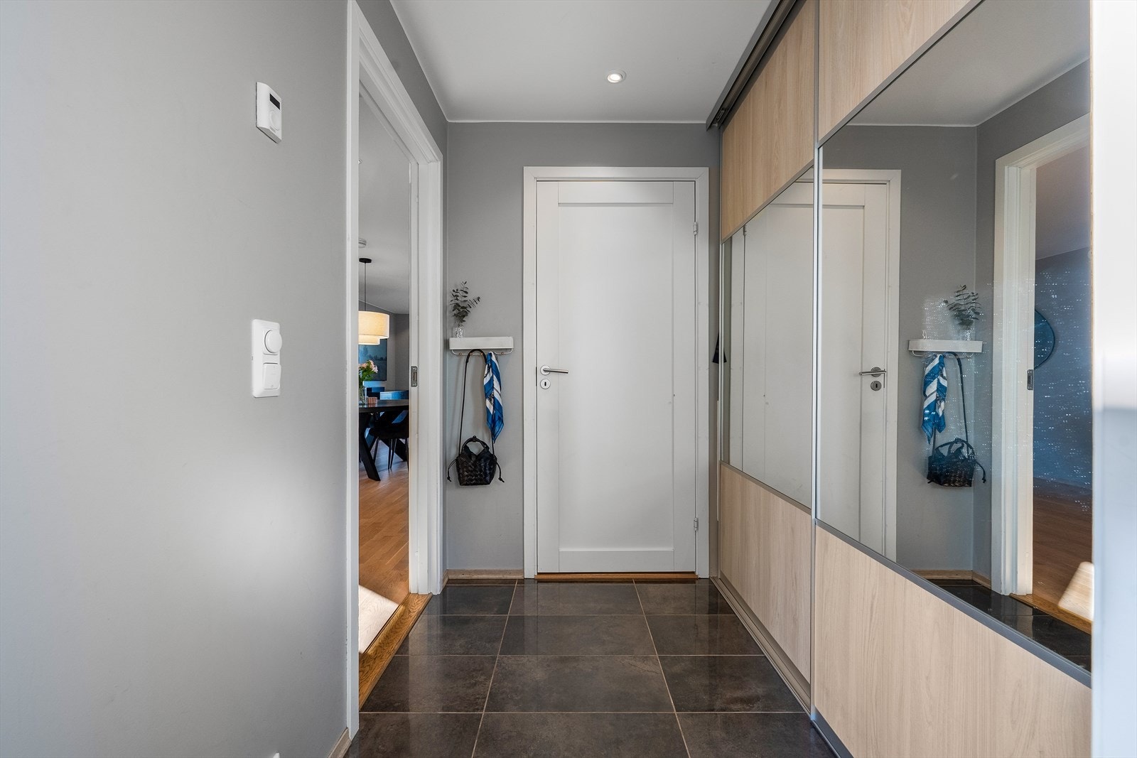 Innbydende entré med flislagt gulv og god oppbevaringsplass i skyvedørsgarderobe. Galleribilde