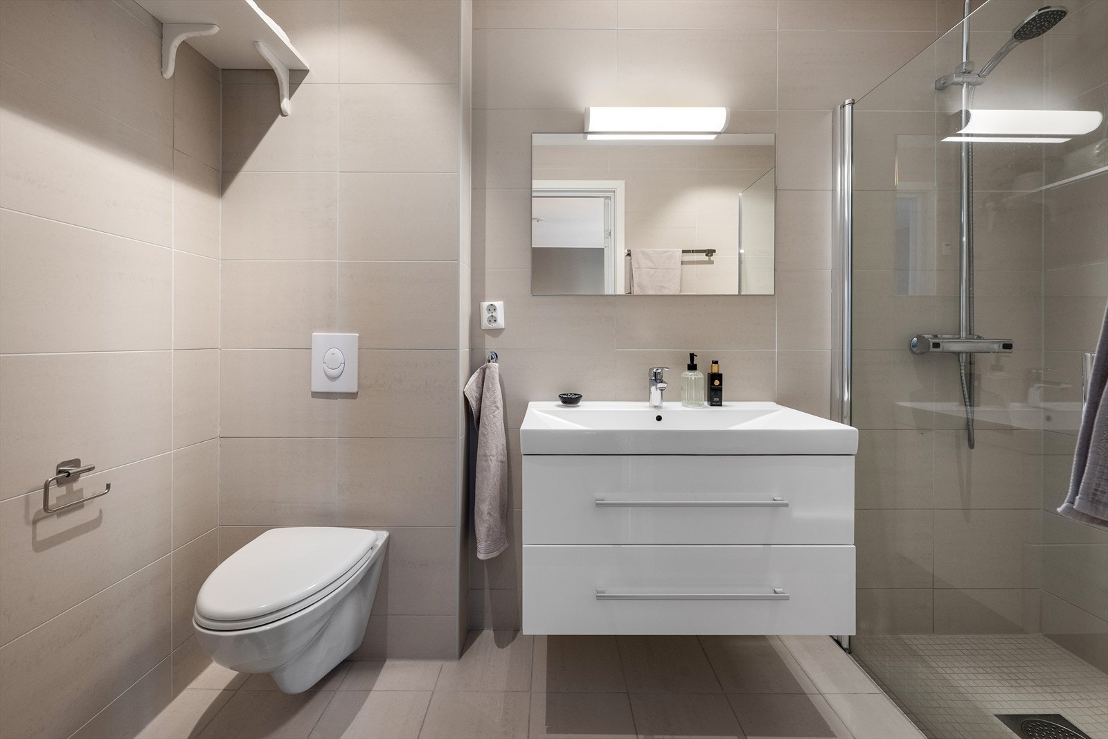 Badet er utstyrt med dusjhjørne, veggmontert WC og servantinnredning. Galleribilde