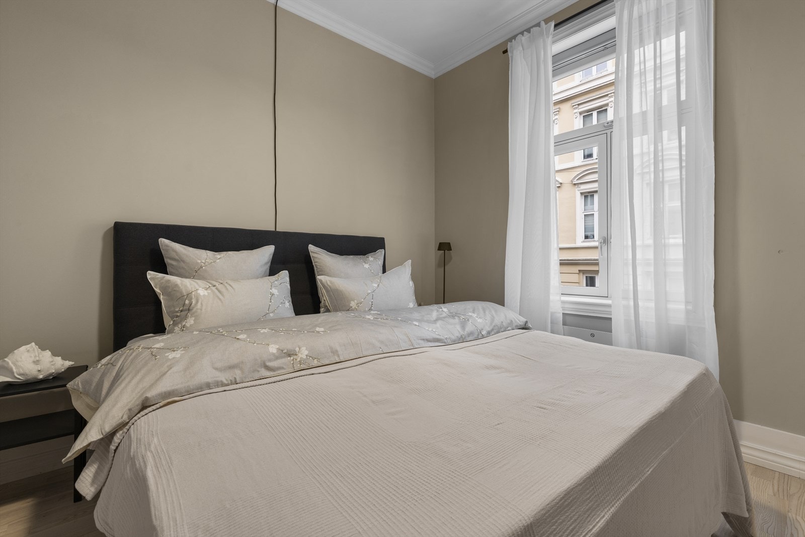 Avbildet er en seng på 180 x 210 cm og nattbord på begge sider. De nye vinduene fra 2024 holder godt på varmen og gir god lydisolasjon. Varmeovn er veggmontert under vinduet. Galleribilde