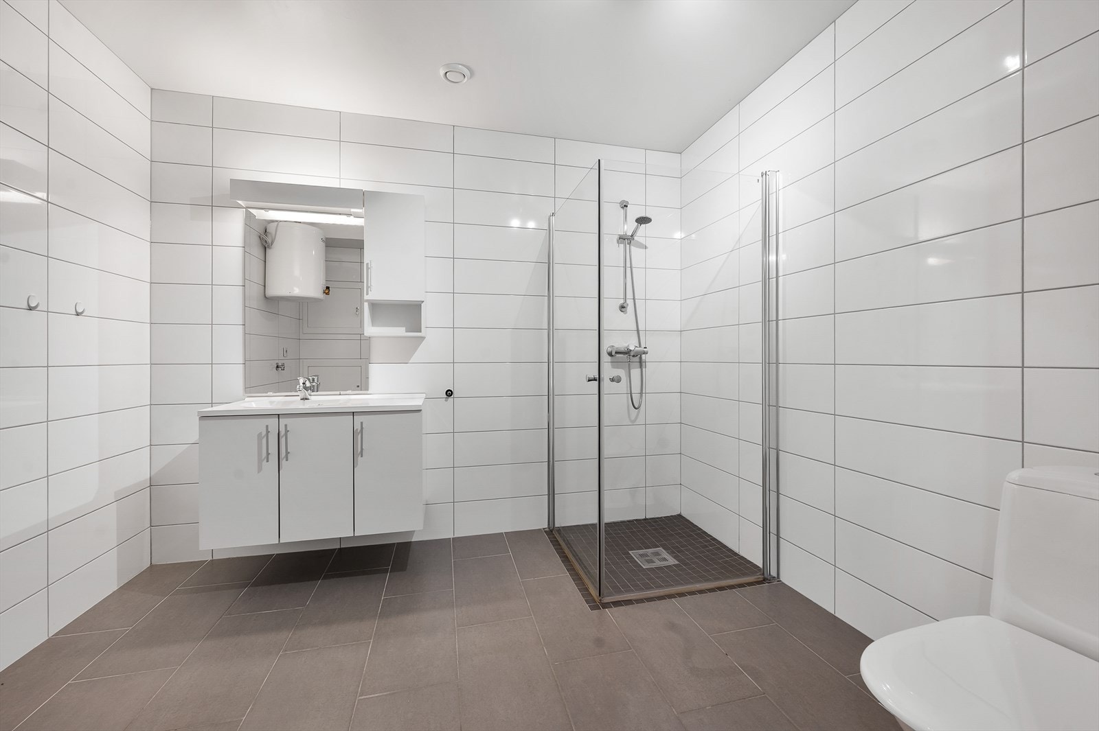 Bad med toalett, dusjhjørne servant og opplegg for vaskemaskin. Galleribilde