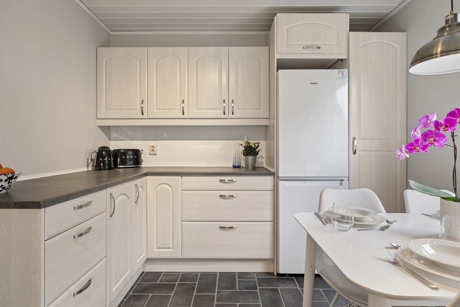 Kjøkkenet har profilerte fronter og benkeplate av laminat Galleribilde