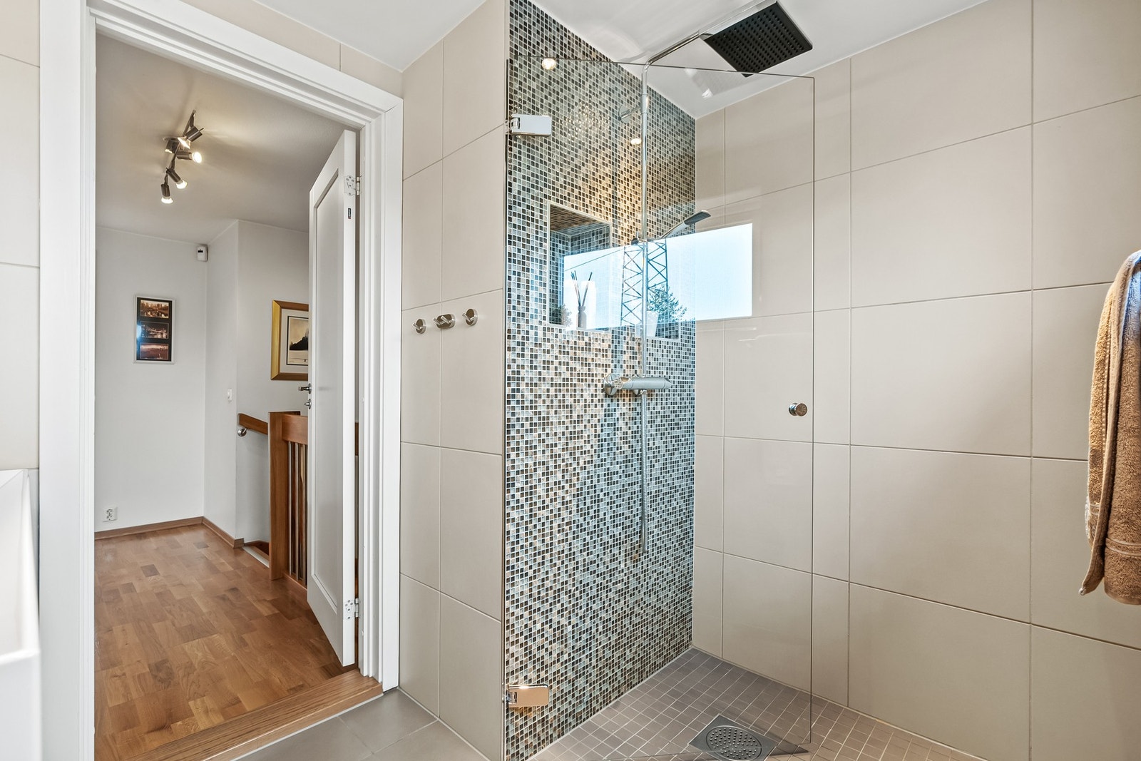 I tillegg til et vegghengt toalett er badet utstyrt med en dusjnisje med mosaikkfliser og regnfallsdusj, samt en elektrisk avtrekksvifte. Galleribilde