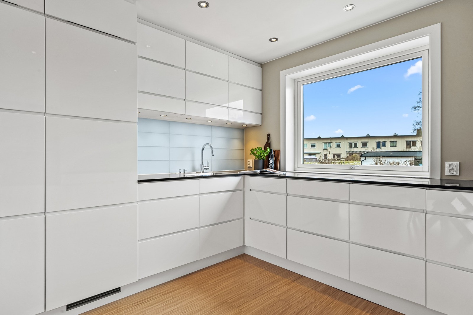 Innredningen fra Kvik har hvite høyglansfronter og sort benkeplate i stein med planlimt kum i stål. Galleribilde