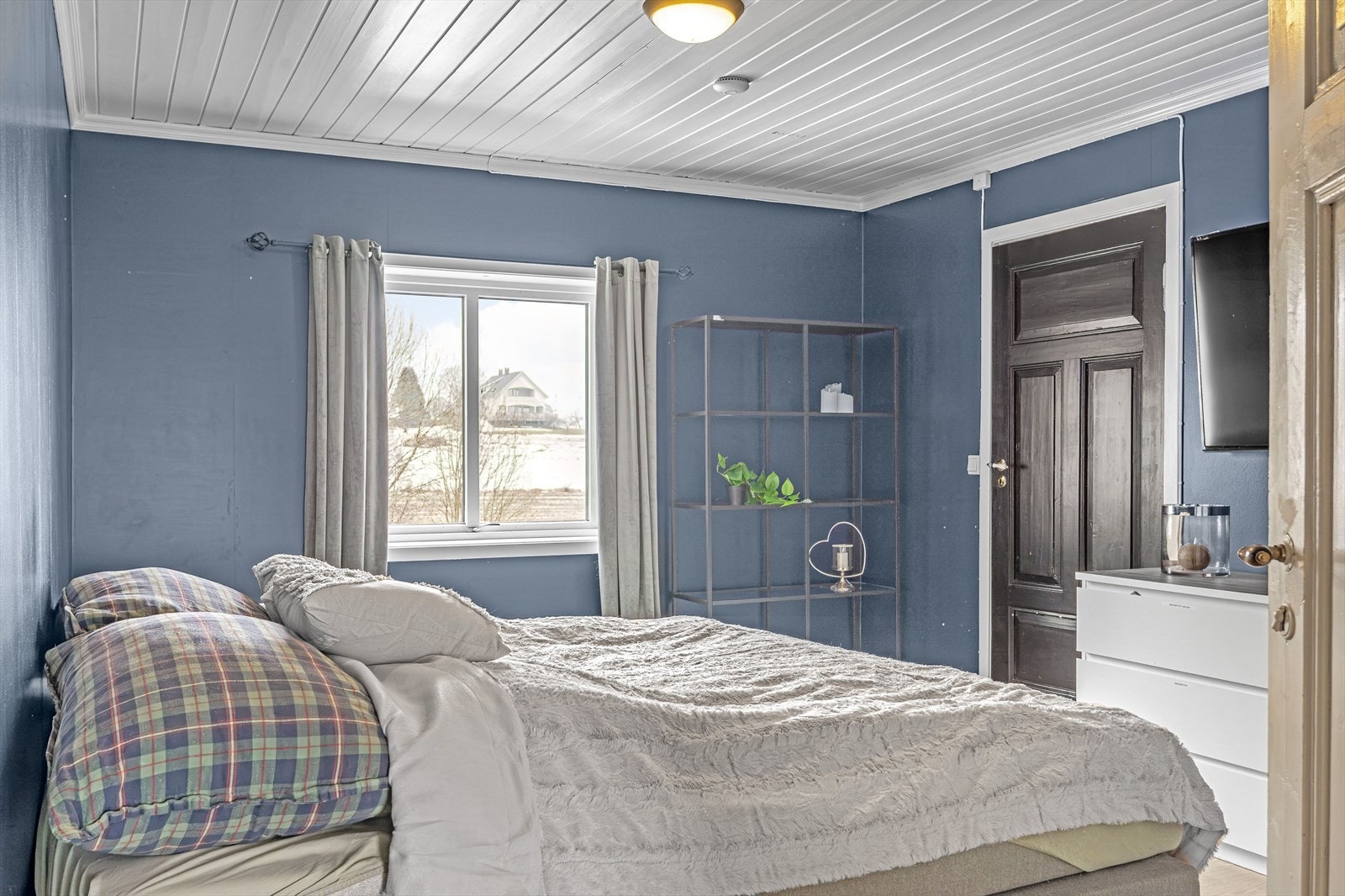 Hovedsoverommet har panelte vegger i en lun blåtone og laminatgulv. Galleribilde