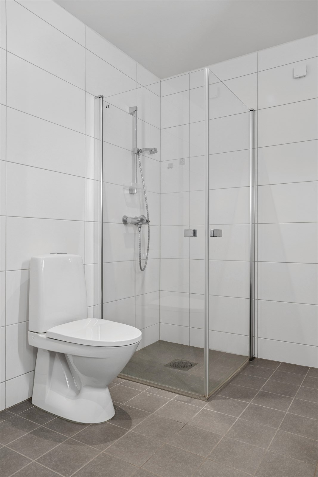 Rommet er utstyrt med vegghengt servantinnredning, dusjhjørne og toalett. Galleribilde