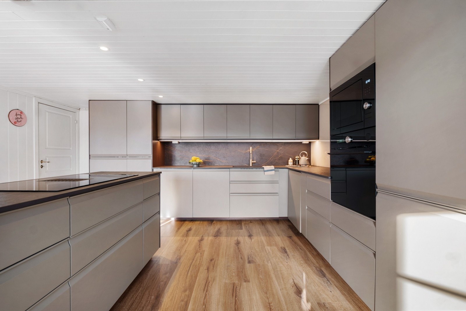 Kjøkkeninnredningen fremstår som både eksklusiv og stilren, med delikate glatte fronter i duse toner som gir et moderne og elegant uttrykk Galleribilde