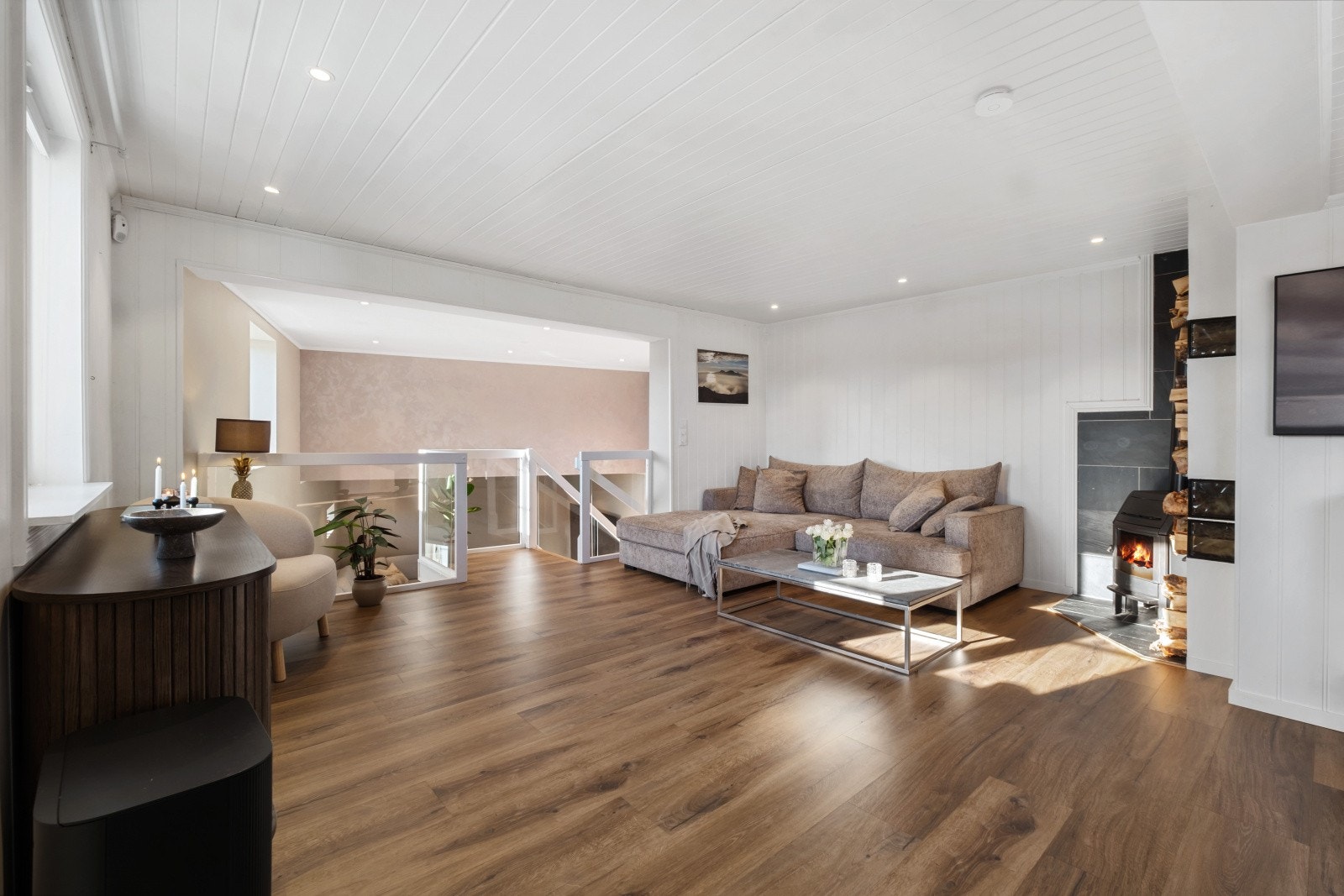 Videre inn i stuen er det god plass til en komfortabel sittegruppe med sofakrok foran ildstedet som skaper en lun og hyggelig atmosfære Galleribilde