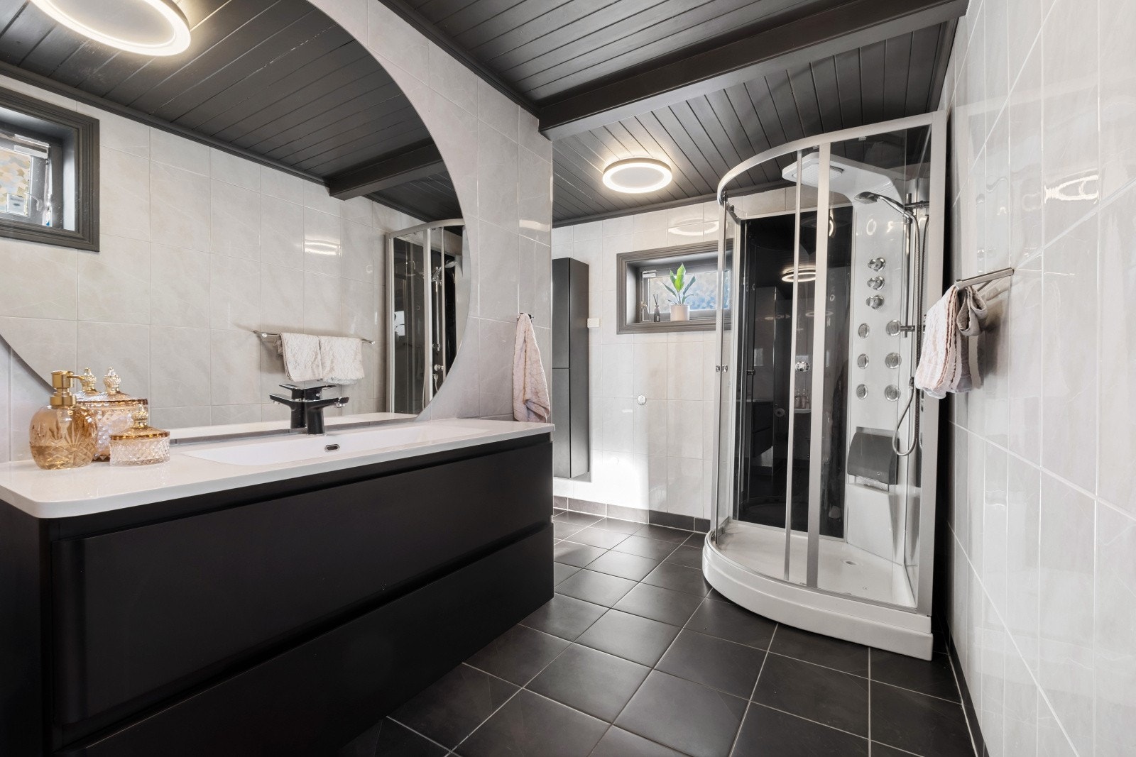 Badet fremstår som delikat og moderne med flislagte vegger og gulv som gir et tidløst uttrykk. Elektriske varmekabler i gulvet sørger for god komfort. Rommet er innredet med en flott baderomsinnredning med heldekkende servant, god skap- og skuffeplass sam Galleribilde