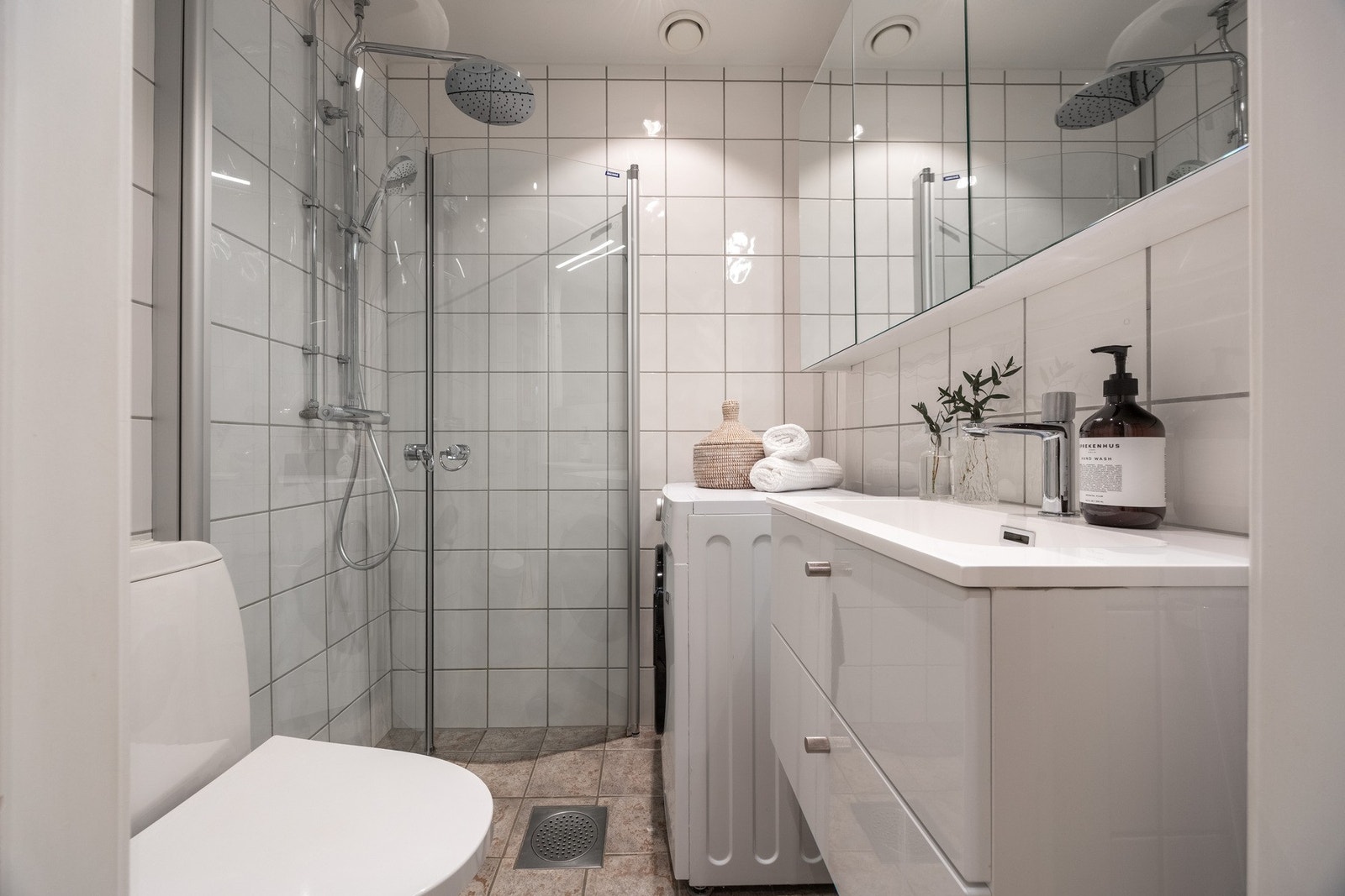 Flislagt bad med dusjhjørne, servant og opplegg for vaskemaskin. Galleribilde