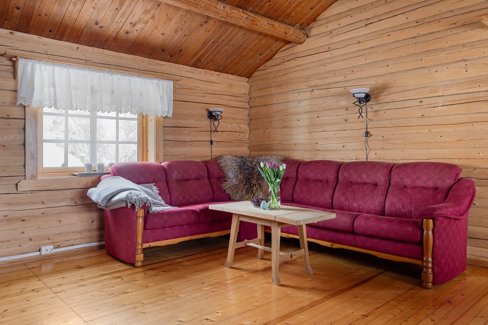 Stue med synlige tømmervegger og tregulv. Galleribilde