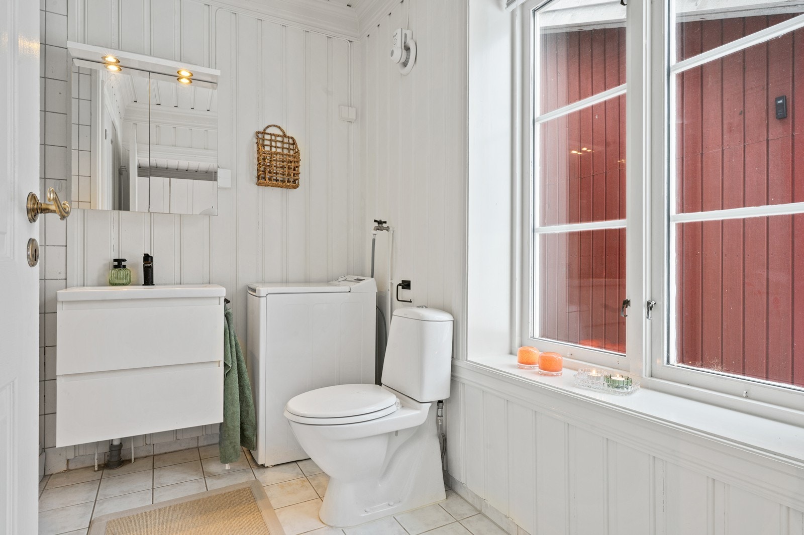 Flislagt bad med servantinnredning og opplegg for vaskemaskin. Galleribilde