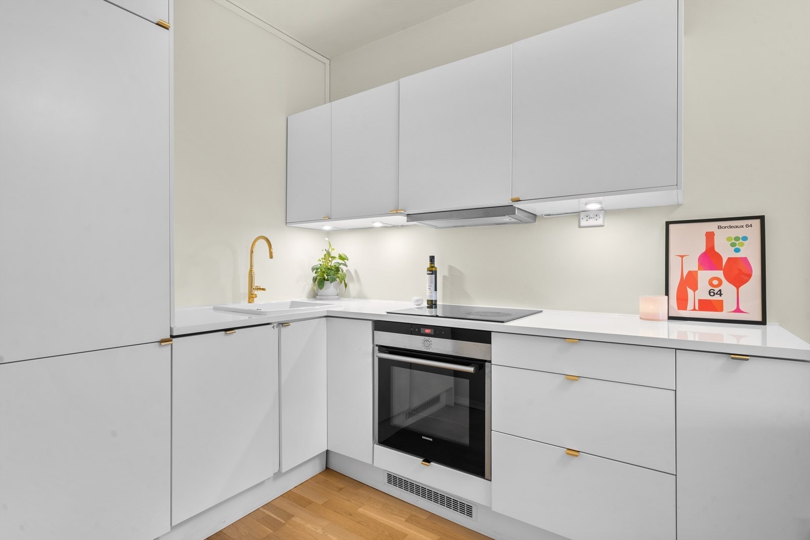 Kjøkkenet fremstår moderne og funksjonelt med glatte fronter, integrerte hvitevarer og praktisk belysning under overskapene. Galleribilde