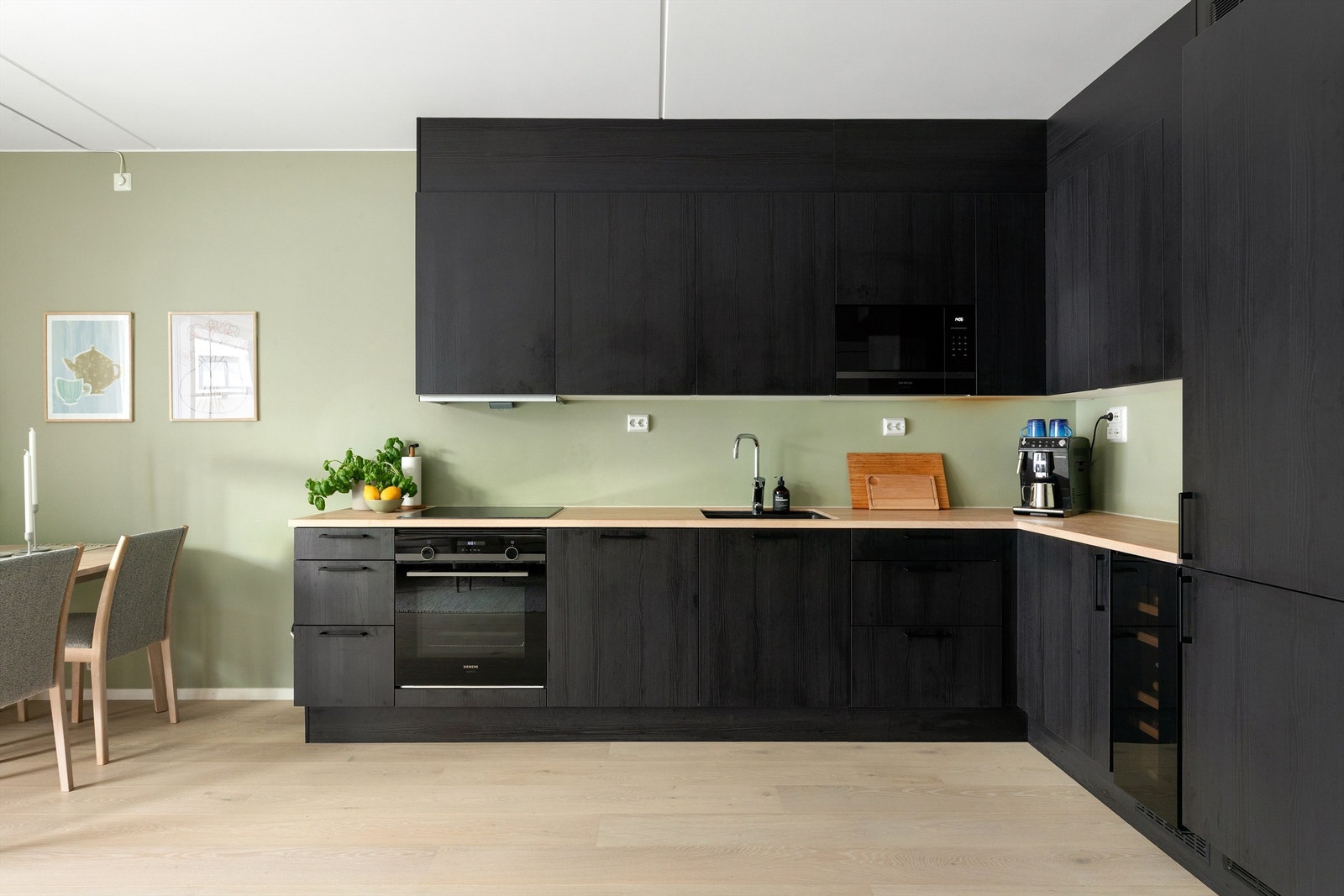 Kjøkkenet har glatte finérdører i mørk brunt eikemønster, med benkeplate i lys eik med underlimt oppvaskkum Galleribilde