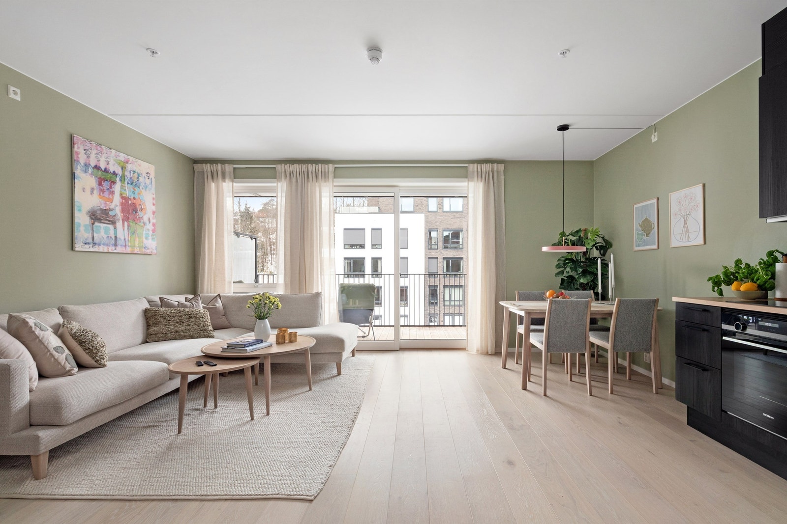 Stuen har store vindusflater som slipper inn godt med naturlig dagslys, kombinasjonen med det lyse 1-stavs parkettgulvet og de duse grønnmalte veggene gir god romfølelse Galleribilde