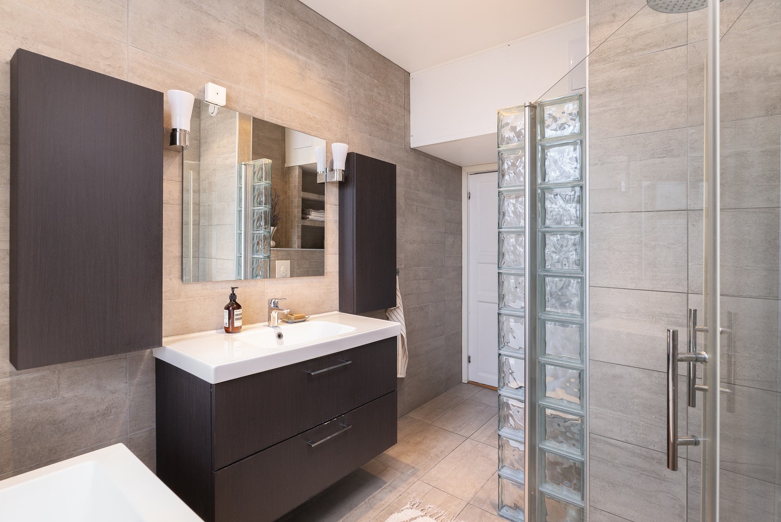 Himlingen er nedsenket med downlights. Det er opplegg for vaskemaskin ved døren med flislagte hyller over. Galleribilde