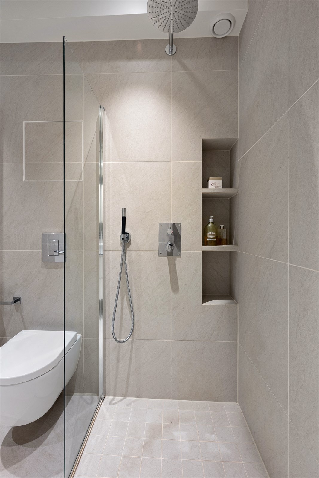 Badet er utstyrt med dobbel dusj med faste felt i herdet glass og innebygde hyller. Galleribilde