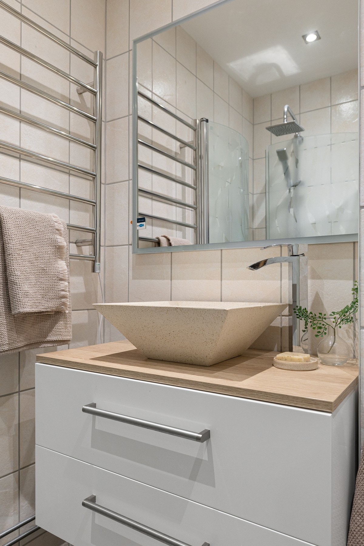 Badet er utstyrt med gulvmontert toalett, dusjhjørne, servantseksjon med skuffer og speil. Galleribilde