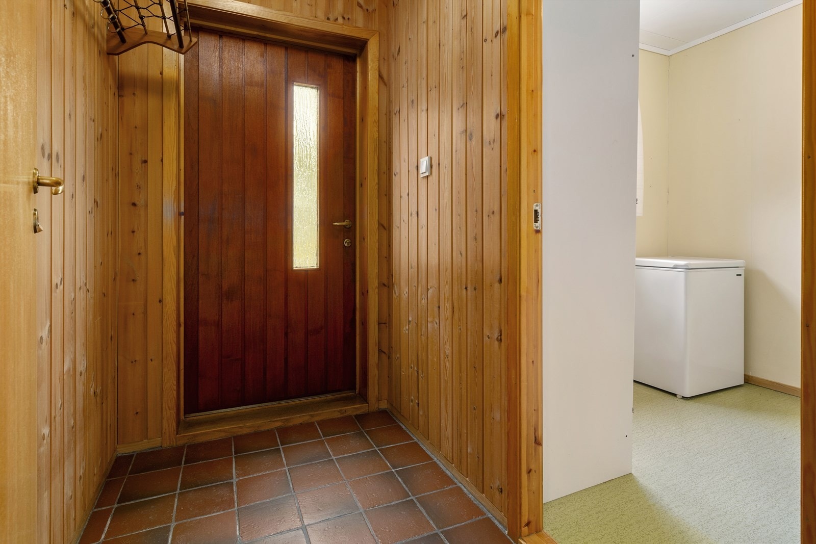 Gangen har flislagt gulv og har panel på vegg. Galleribilde