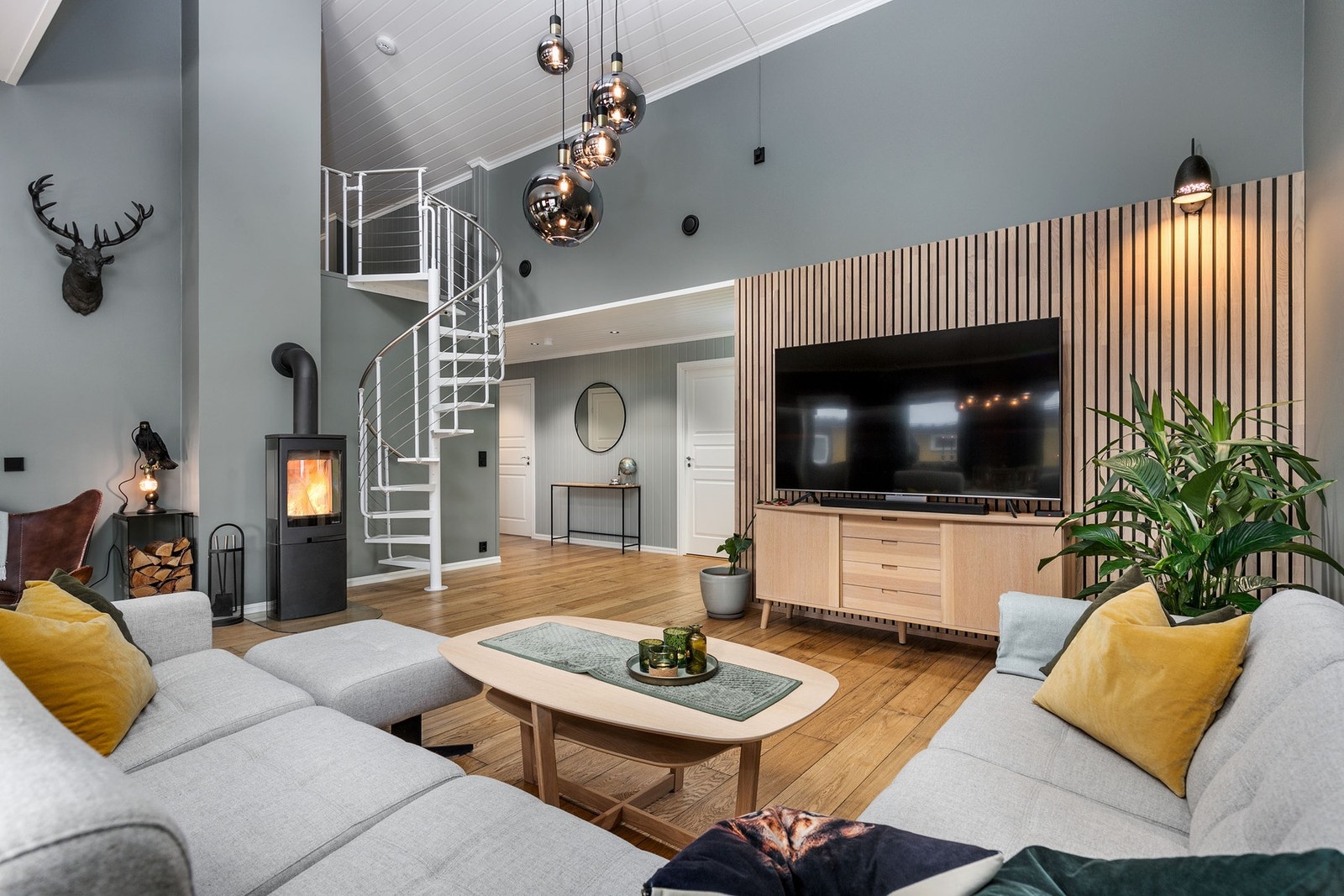 Rommet har moderne innredning med peis og spiraltrapp, høyt tak og god belysning. Galleribilde