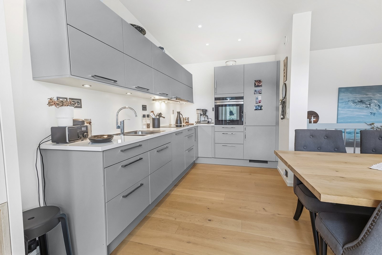 Kjøkken har innredning fra Norema i lys grå utførelse og er utstyrt med integrerte hvitevarer. Det er også lagt downlights under overskap for godt arbeidslys på benk. Galleribilde