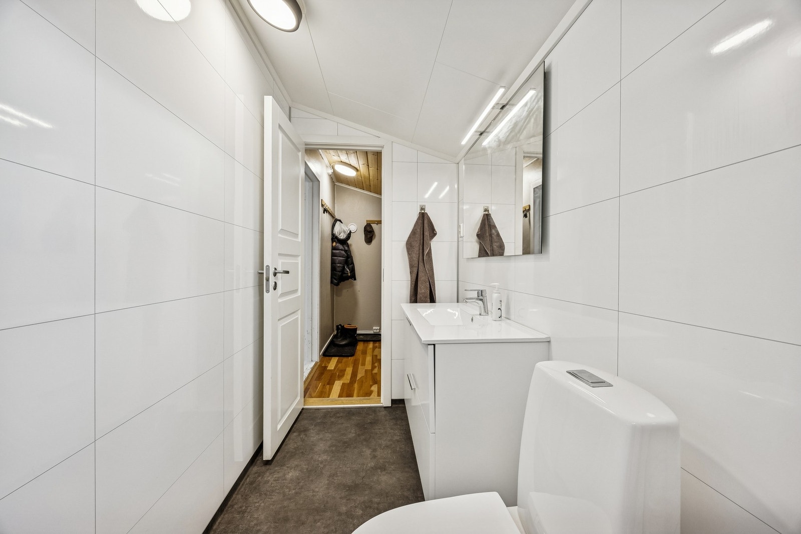 Badet er innredet med nedfelt servant, dusj med forheng, toalett og opplegg for vaskemaskin Galleribilde