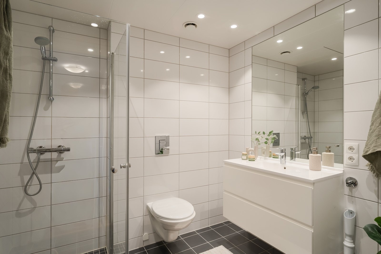 Flislagt og moderne baderom, utført som praktisk baderomskabin produsert på fabrikk. Badet har keramiske fliser på gulv og vegger samt hvite ferdigelementer og innfelte LED-spotter i himlingen som gir et stilrent uttrykk og godt lys. Galleribilde